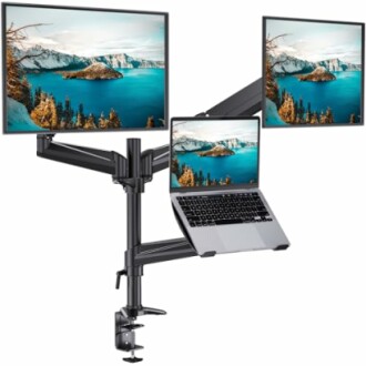 Triple monitor and laptop stand setup with scenic lake images on screens.